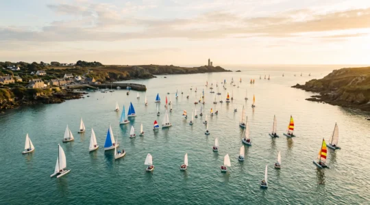 Vue panoramique d'une baie de Loire-Atlantique avec plusieurs voiliers et catamarans de tailles differentes naviguant cote a cote, illustrant la diversite des ecoles de voile