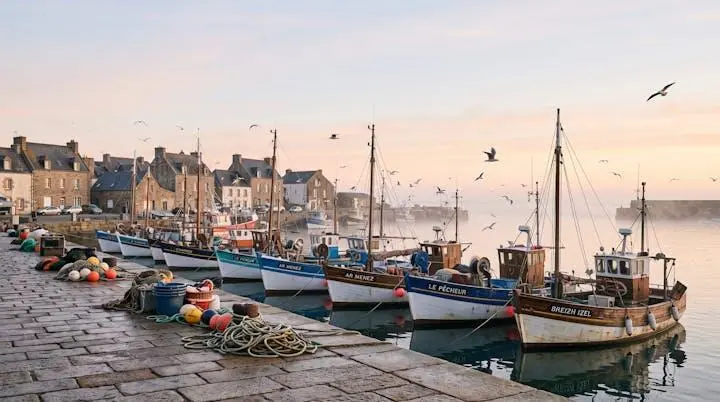 Bateaux de peche traditionnels amarres dans un port de Loire-Atlantique au lever du jour, ambiance embruns et lumiere doree